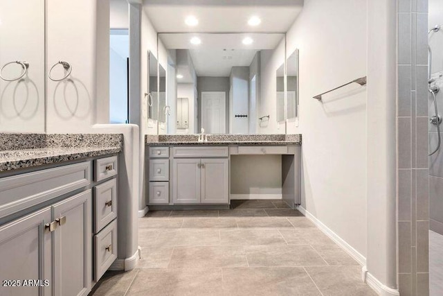 full bath with two vanities, a sink, and a tile shower