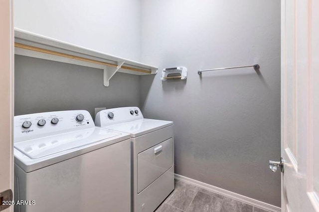 clothes washing area featuring laundry area, baseboards, and washer and clothes dryer