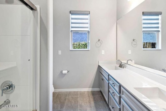 full bathroom with double vanity, tile patterned floors, a sink, and baseboards