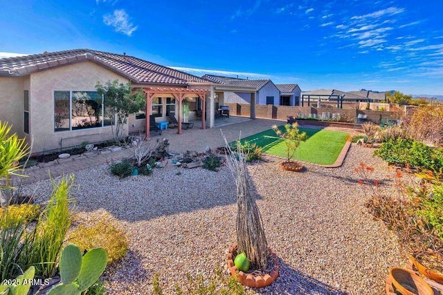 rear view of property featuring a patio, a tile roof, a fenced backyard, and stucco siding