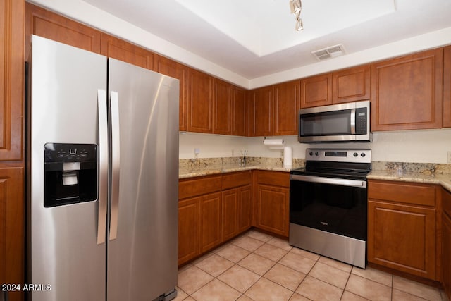 kitchen featuring light stone countertops, appliances with stainless steel finishes, and light tile patterned flooring