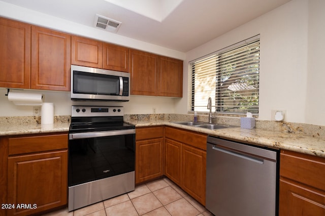 kitchen featuring stainless steel appliances, light stone countertops, sink, and light tile patterned flooring