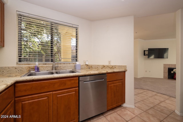 kitchen with light carpet, stainless steel dishwasher, sink, and a tile fireplace