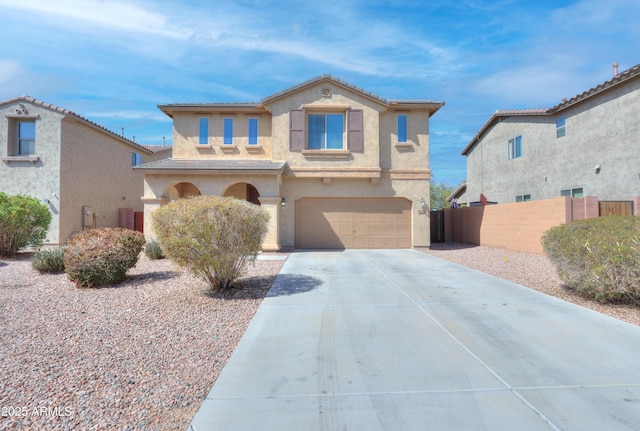 mediterranean / spanish-style home with stucco siding, an attached garage, concrete driveway, and fence