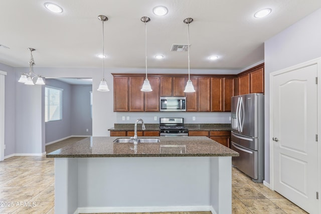 kitchen featuring visible vents, dark stone counters, a sink, stainless steel appliances, and pendant lighting