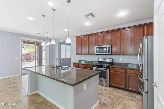 kitchen featuring visible vents, a center island with sink, hanging light fixtures, stainless steel appliances, and a sink