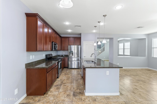 kitchen with visible vents, dark stone counters, a sink, hanging light fixtures, and appliances with stainless steel finishes