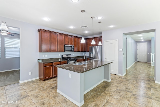 kitchen featuring visible vents, a kitchen island with sink, a sink, dark stone countertops, and stainless steel appliances