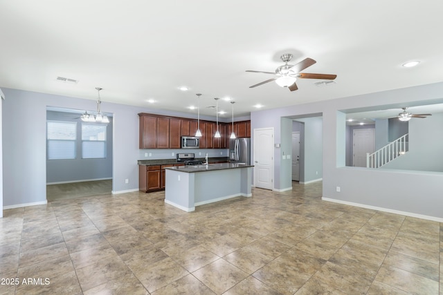 kitchen featuring stainless steel appliances, dark countertops, visible vents, and open floor plan