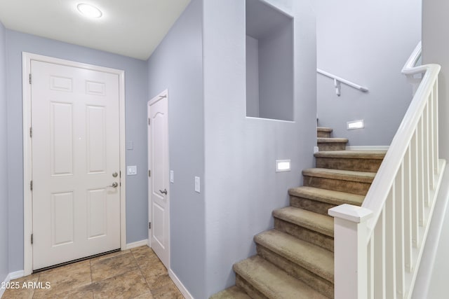 foyer entrance with stairway and baseboards