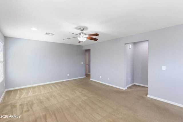 empty room featuring a ceiling fan, baseboards, visible vents, and light carpet