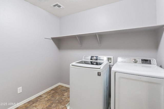 washroom with laundry area, separate washer and dryer, visible vents, and baseboards