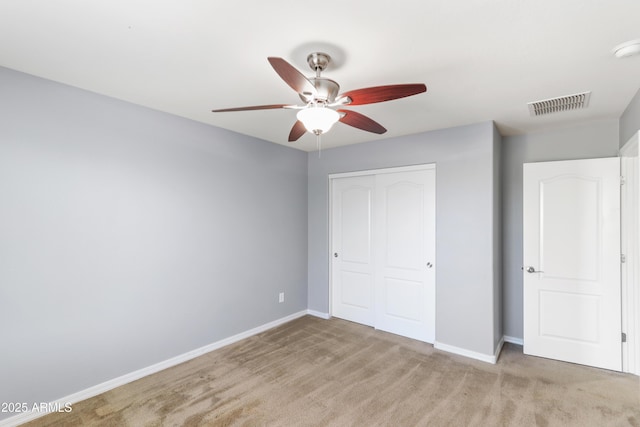 unfurnished bedroom with visible vents, baseboards, ceiling fan, light colored carpet, and a closet