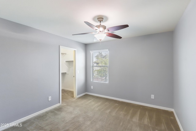 unfurnished bedroom with a closet, carpet, a walk in closet, and baseboards