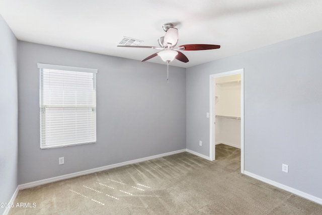 carpeted empty room with visible vents, baseboards, and a ceiling fan