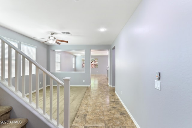 hall with visible vents, baseboards, and stairs