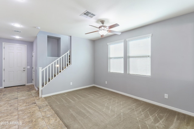 empty room with visible vents, ceiling fan, stairway, and baseboards