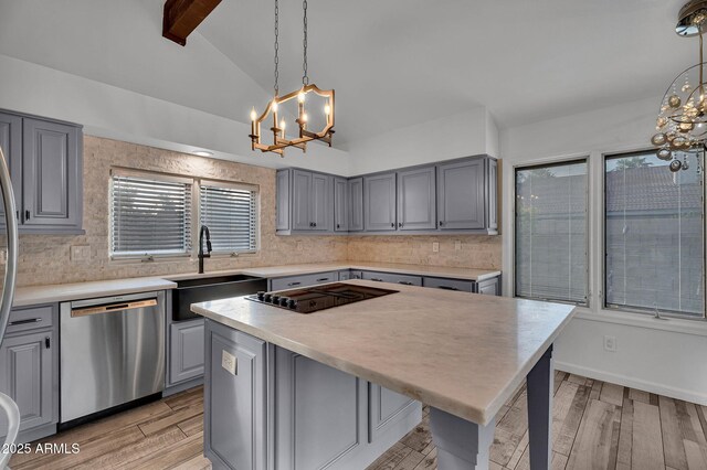 kitchen featuring a chandelier, stainless steel dishwasher, gray cabinets, and a sink