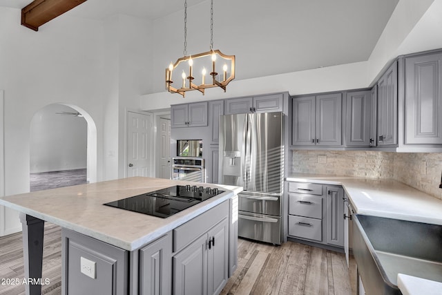 kitchen featuring gray cabinetry, appliances with stainless steel finishes, a chandelier, light countertops, and tasteful backsplash
