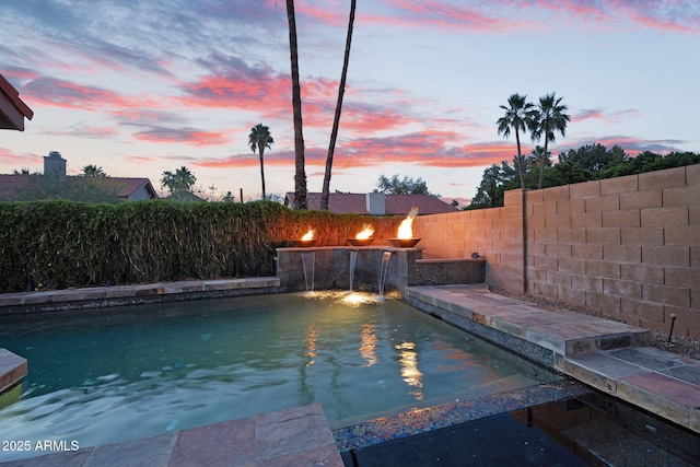 pool at dusk with a fenced backyard