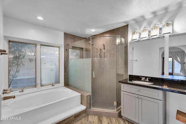 bathroom featuring a shower stall, vanity, a bath, wood finished floors, and recessed lighting