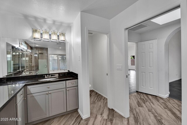 full bath featuring a shower stall, wood finished floors, vanity, and baseboards