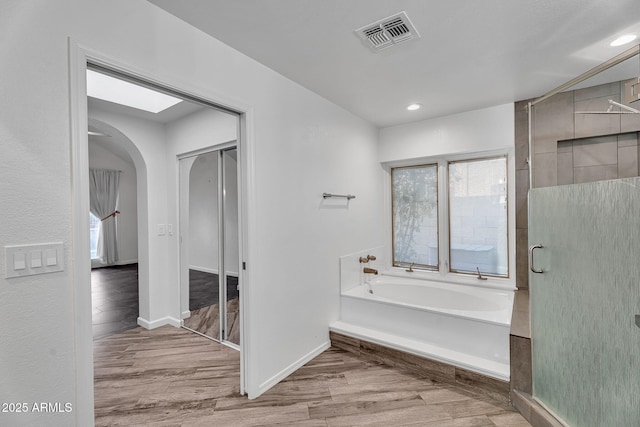 bathroom featuring plenty of natural light, wood finished floors, a garden tub, recessed lighting, and an enclosed shower