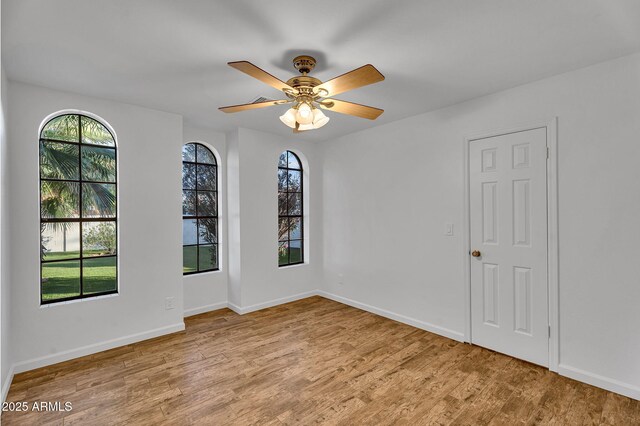 unfurnished room featuring wood finished floors, ceiling fan, and baseboards