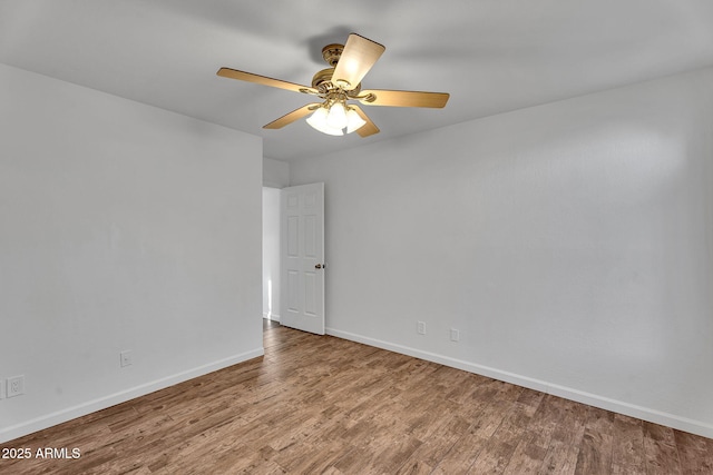 spare room featuring baseboards, wood finished floors, and a ceiling fan