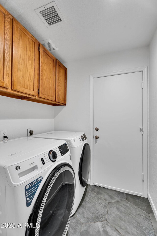 clothes washing area featuring cabinet space, independent washer and dryer, and baseboards