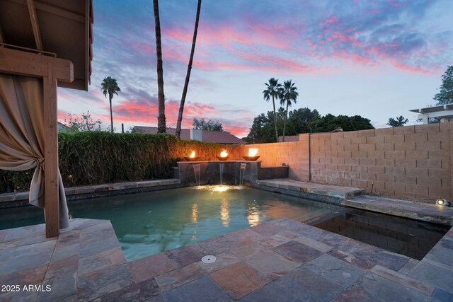 pool at dusk featuring a fenced backyard and a patio area