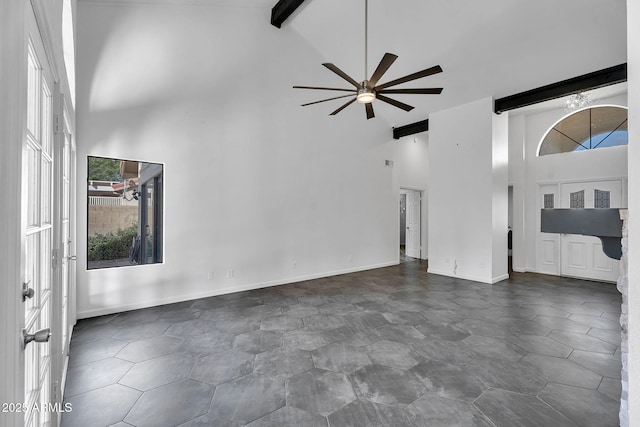 unfurnished living room featuring high vaulted ceiling, ceiling fan, plenty of natural light, beamed ceiling, and baseboards