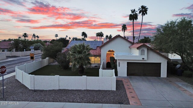 view of front facade featuring solar panels, stucco siding, concrete driveway, and a garage