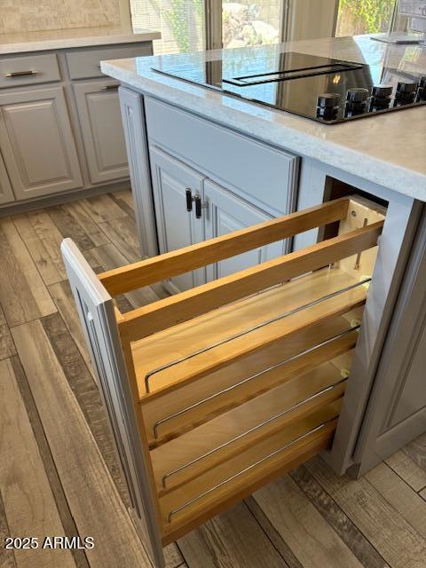 kitchen view of light countertops, black electric stovetop, and light wood-style flooring