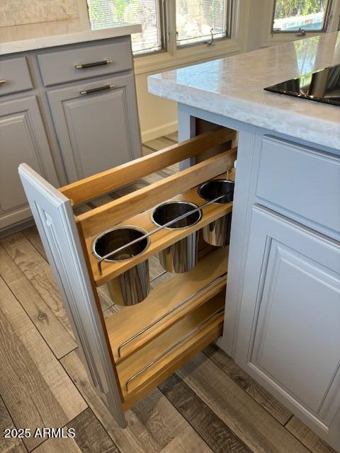 kitchen view of light countertops, light wood finished floors, black electric cooktop, and gray cabinetry