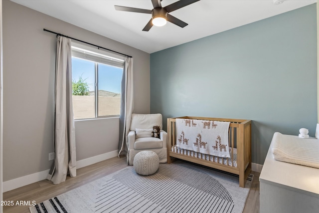 5430 W Notch Hill Rd, Laveen, AZ 85339 - bedroom with baseboards, light wood-type flooring, a nursery area, and ceiling fan