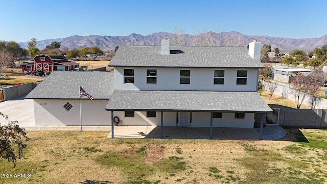 back of property with a mountain view, a lawn, and a patio area