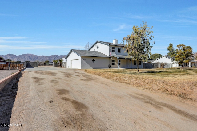 view of front facade featuring a garage, a mountain view, and a front lawn