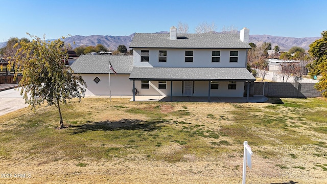 rear view of house featuring a yard, a mountain view, and a patio