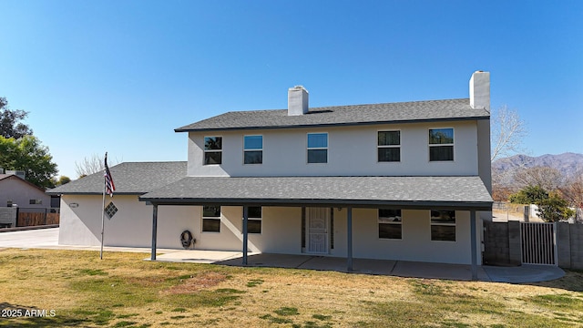 back of property featuring a mountain view, a patio area, and a lawn