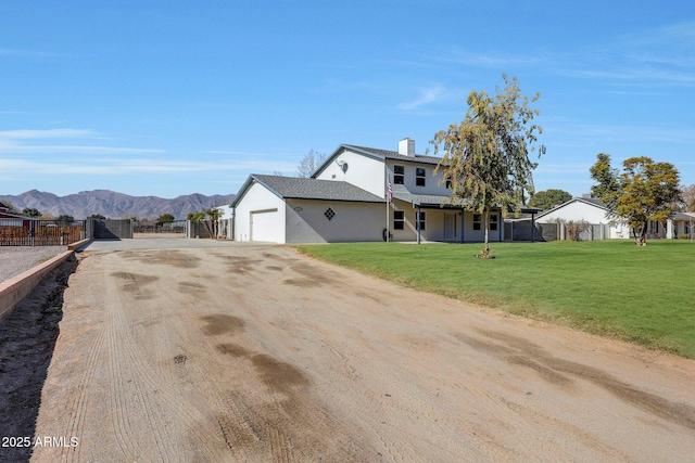 exterior space with a garage, a mountain view, and a front yard