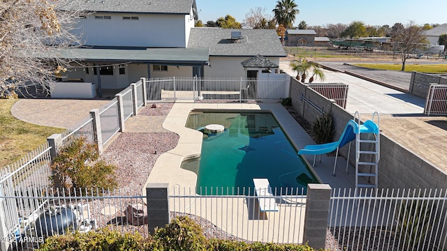 view of pool with a water slide, a diving board, and a patio area