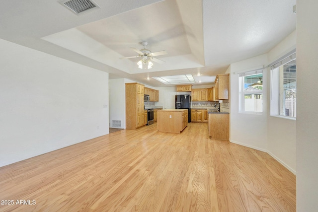 kitchen with stove, a center island, black fridge with ice dispenser, a tray ceiling, and light hardwood / wood-style flooring