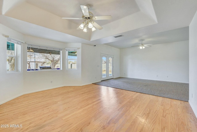 unfurnished room with french doors, a tray ceiling, ceiling fan, and light hardwood / wood-style flooring