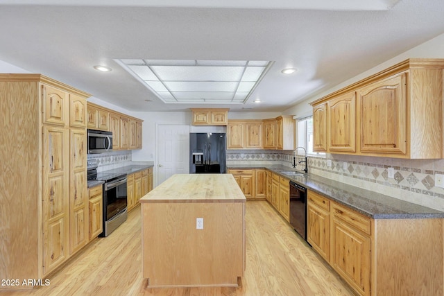 kitchen with a kitchen island, sink, light wood-type flooring, and black appliances