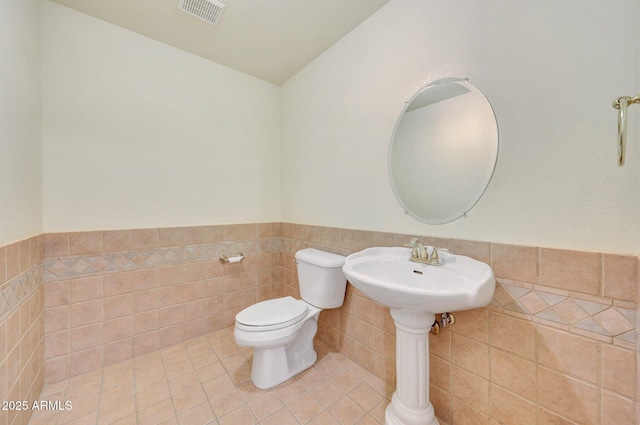 bathroom with tile patterned flooring, tile walls, and toilet