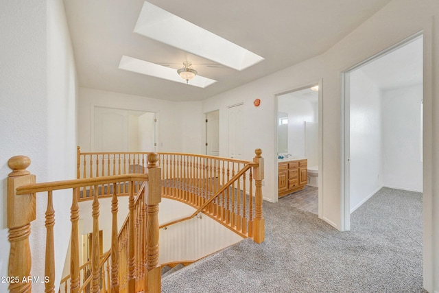 hall with light colored carpet and a skylight