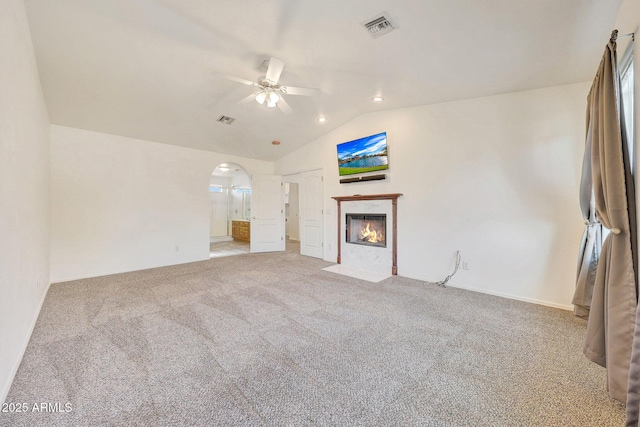 unfurnished living room featuring ceiling fan, lofted ceiling, a fireplace, and carpet