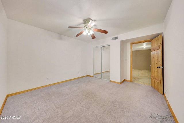 unfurnished bedroom featuring light carpet, a closet, and ceiling fan