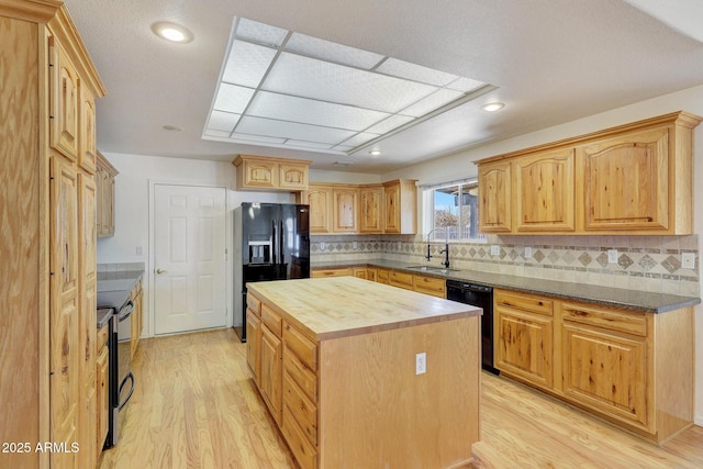 kitchen featuring light wood-type flooring, wooden counters, sink, and black appliances